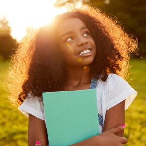 smiling black middle school girl in a field with sun behind her 1000