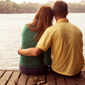 Couple sitting on a dock hugging 1000