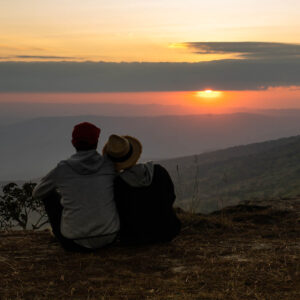 Couple sitting on mountain side watching the sunset 1000
