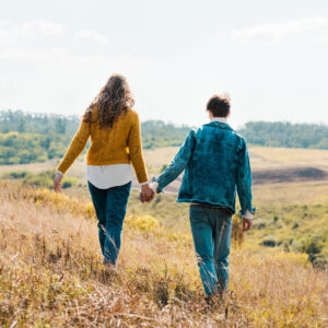 Couple walking through field holding hands 1000