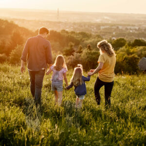 Family walking together in a grassy field with sun going down 1000