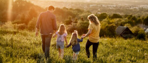 Family walking together in a grassy field with sun going down 2560