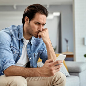 Man looking at images intently on his phone, needs to get help with group therapy at Wyndhurst Counseling and Wellness 1000