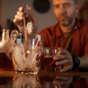 Man putting ice in alcoholic drink