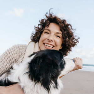 Woman with dog at the Beach content after going through counseling at Wyndurst Counseling and Wellness