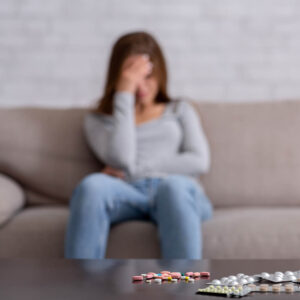 Woman sitting on sofa with pills on the table really upset needs to contact Wyndhurst Counseling and Wellness in Lynchburg Va 1000