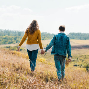 Young couple holding hands and walkng through a field 1000