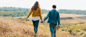 Young couple holding hands and walkng through a field 2560