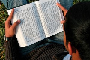 Young man in the grass reading the word of God 600